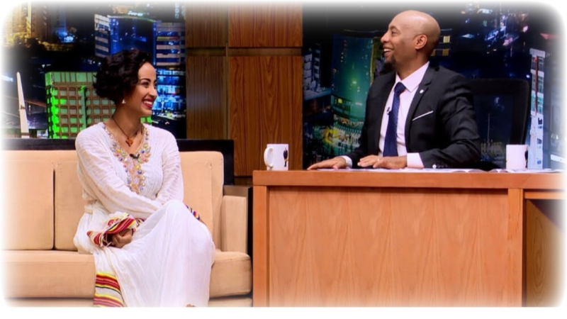 Ethiopian talk show, the host Seifu Fantahun talking with a woman sitting on a couch.